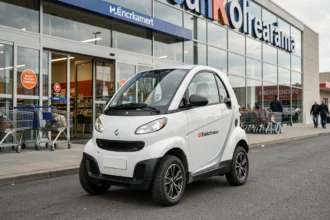 Petite voiture sans permis garée devant l'entrée d'un hypermarché Leclerc