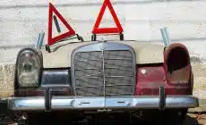 an old car with a warning sign on top of it